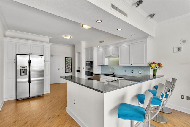 kitchen featuring white cabinets, sink, decorative backsplash, appliances with stainless steel finishes, and kitchen peninsula