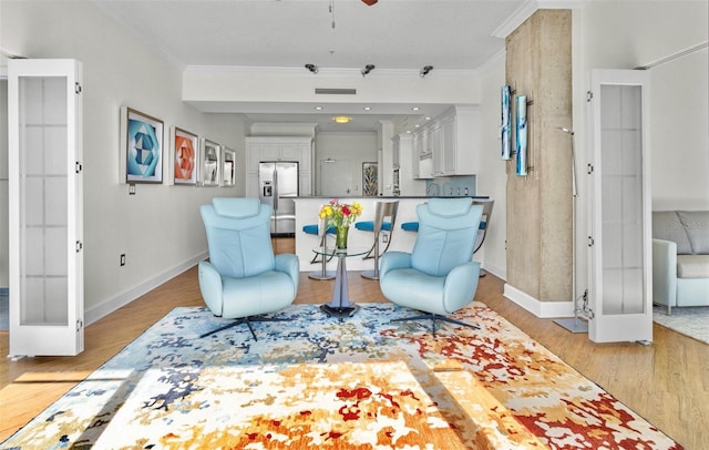 living area featuring french doors, light wood-type flooring, ceiling fan, and ornamental molding