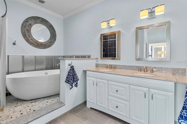 full bathroom featuring a freestanding bath, crown molding, double vanity, and a sink