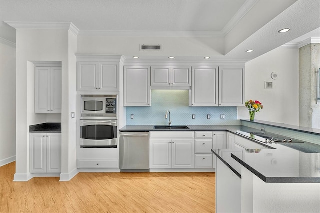 kitchen featuring visible vents, a sink, dark countertops, stainless steel appliances, and a peninsula