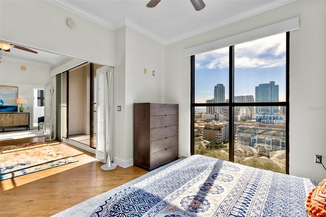 bedroom with a city view, crown molding, baseboards, and wood finished floors