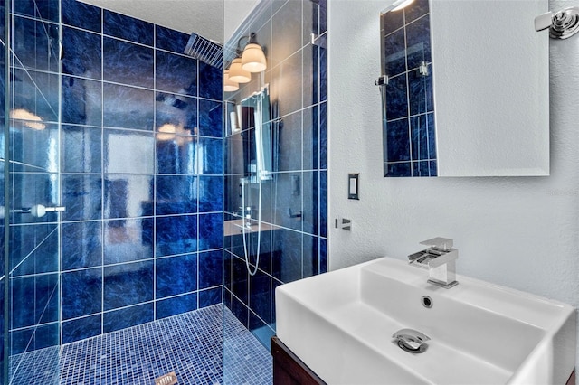 full bathroom featuring vanity, a shower stall, and a textured wall