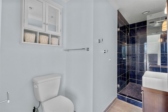 bathroom with vanity, toilet, and tiled shower