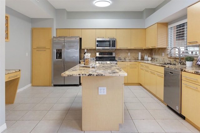 kitchen with light tile patterned flooring, stainless steel appliances, light brown cabinetry, and a center island