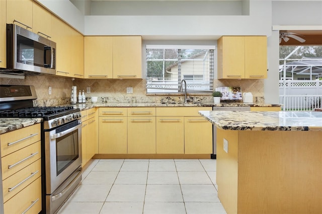 kitchen with sink, light stone countertops, appliances with stainless steel finishes, light tile patterned floors, and light brown cabinetry