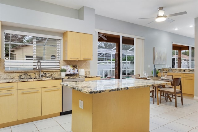 kitchen featuring stainless steel dishwasher, light brown cabinets, and light stone counters