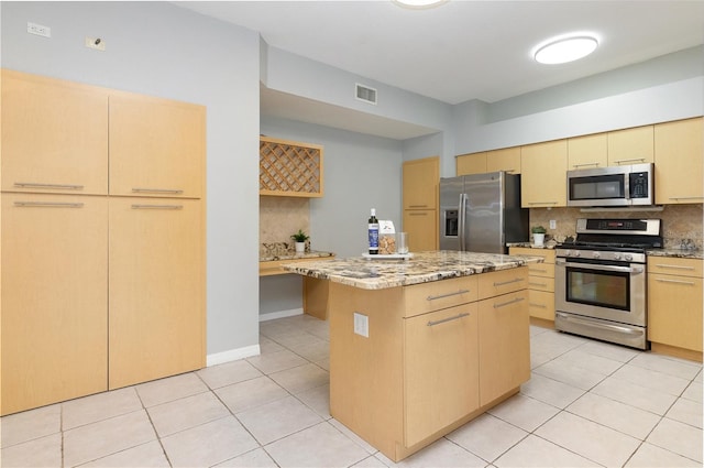 kitchen with backsplash, a kitchen island, stainless steel appliances, light tile patterned floors, and light brown cabinetry