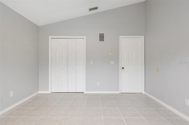 unfurnished bedroom featuring light tile patterned floors, a closet, and lofted ceiling