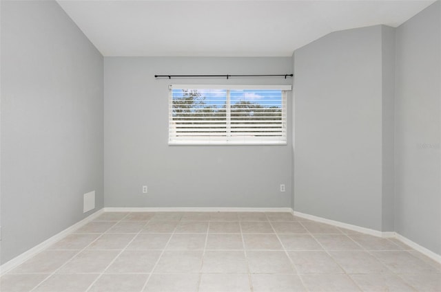 tiled spare room featuring vaulted ceiling