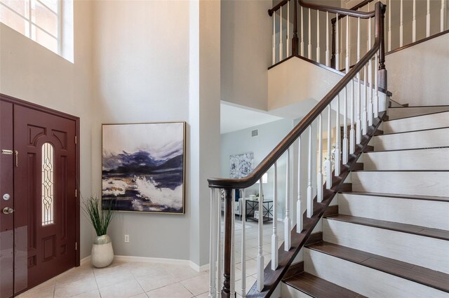 entrance foyer with light tile patterned floors and a towering ceiling