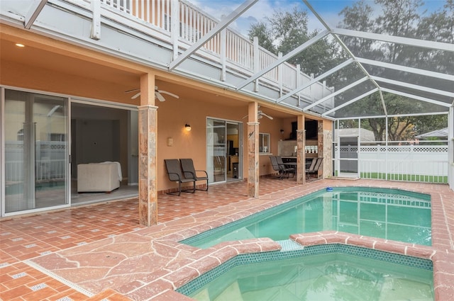 view of pool featuring glass enclosure, a patio area, and ceiling fan