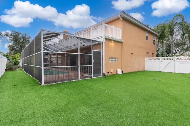 back of house with a fenced in pool, glass enclosure, a lawn, and a balcony