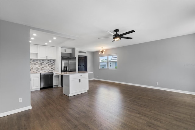 kitchen featuring appliances with stainless steel finishes, tasteful backsplash, ceiling fan with notable chandelier, a center island, and white cabinetry