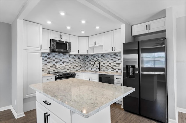 kitchen with decorative backsplash, white cabinetry, a kitchen island, and appliances with stainless steel finishes