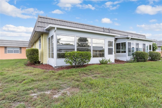 rear view of property featuring a yard and a sunroom