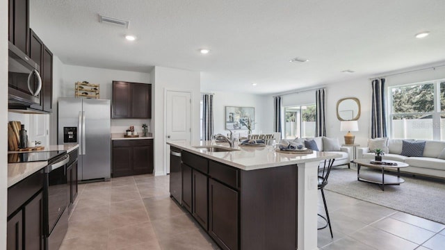 kitchen featuring sink, a kitchen breakfast bar, a center island with sink, light tile patterned floors, and appliances with stainless steel finishes