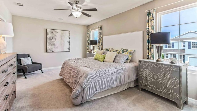 carpeted bedroom featuring multiple windows and ceiling fan