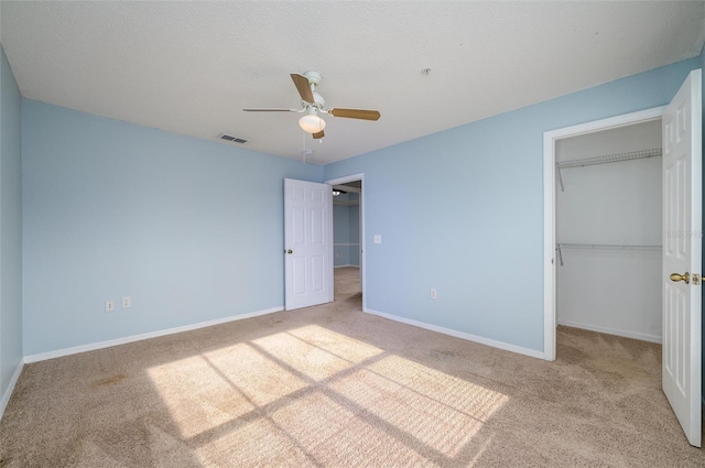 unfurnished bedroom featuring ceiling fan, a closet, light colored carpet, and a textured ceiling