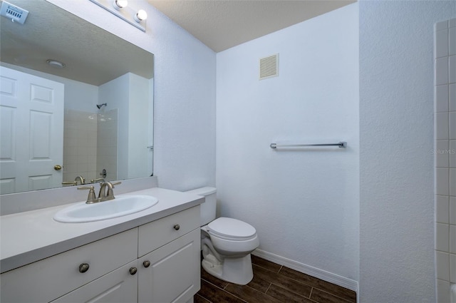 bathroom with a textured ceiling, vanity, toilet, and walk in shower