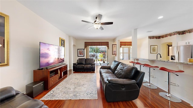 living room featuring dark hardwood / wood-style flooring, ceiling fan, and sink