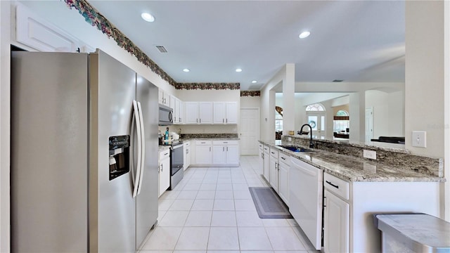 kitchen featuring sink, stainless steel appliances, light stone counters, kitchen peninsula, and white cabinets