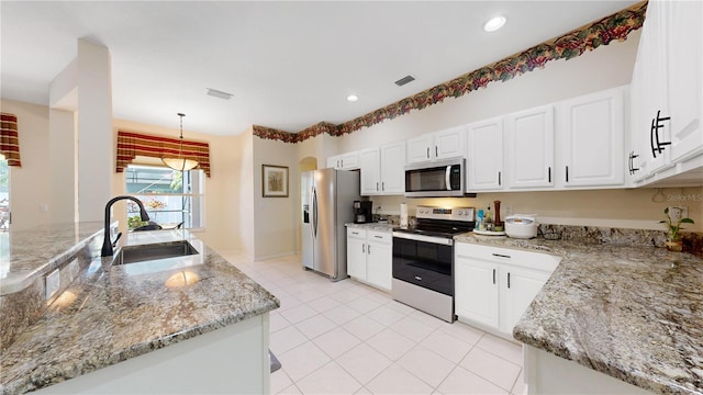 kitchen with light stone counters, stainless steel appliances, sink, decorative light fixtures, and white cabinets