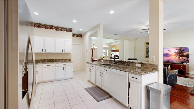 kitchen featuring white dishwasher, white cabinets, stainless steel fridge with ice dispenser, and sink