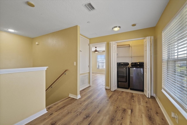 hall featuring a textured ceiling, light wood-type flooring, and washer and clothes dryer