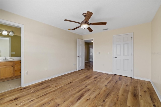 unfurnished bedroom featuring ensuite bathroom, light hardwood / wood-style flooring, ceiling fan, and sink