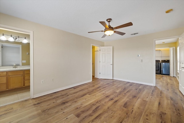 unfurnished bedroom with ensuite bathroom, sink, light hardwood / wood-style flooring, washer and dryer, and ceiling fan