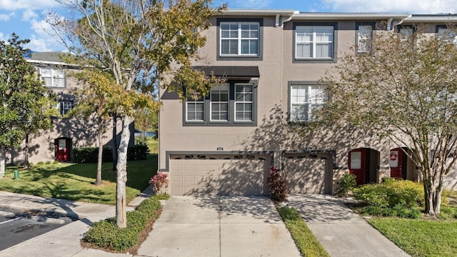 townhome / multi-family property featuring a garage and a front lawn