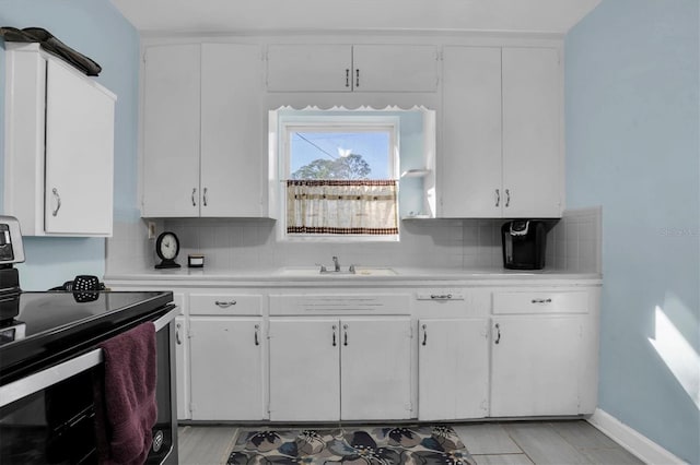 kitchen featuring white cabinets, backsplash, stainless steel range with electric stovetop, and sink