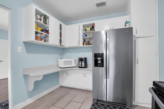 kitchen featuring white cabinetry, stainless steel fridge with ice dispenser, and range with electric stovetop