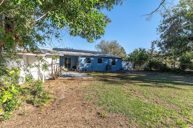 back of house featuring solar panels and a yard