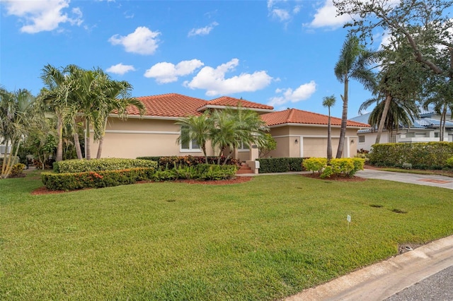 mediterranean / spanish home featuring a front lawn and a garage