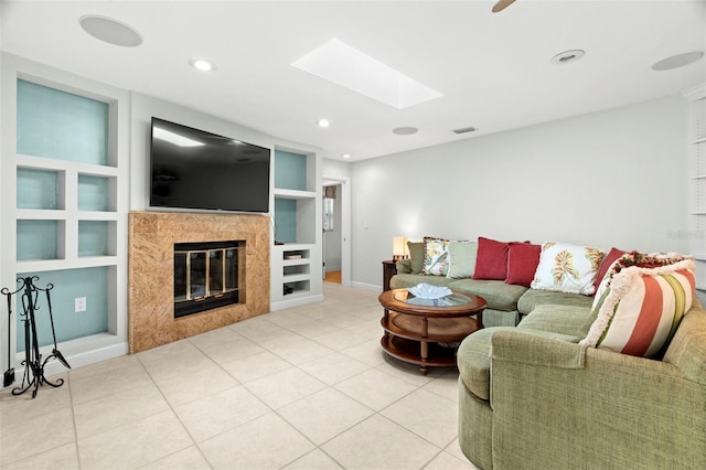 living room featuring tile patterned floors, built in shelves, a high end fireplace, and a skylight