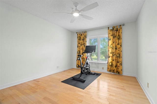 exercise area with ceiling fan, light hardwood / wood-style flooring, and a textured ceiling