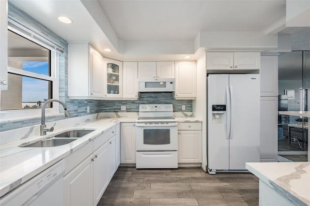 kitchen with white appliances, white cabinets, sink, tasteful backsplash, and light stone counters