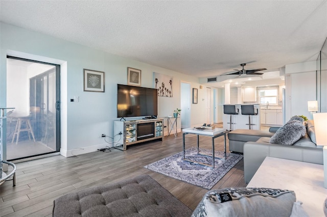 living room with ceiling fan, hardwood / wood-style floors, a textured ceiling, and sink