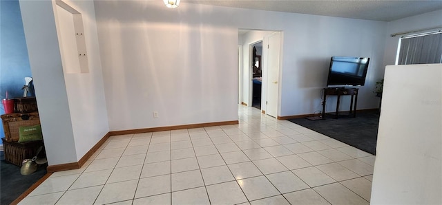 tiled empty room featuring a textured ceiling