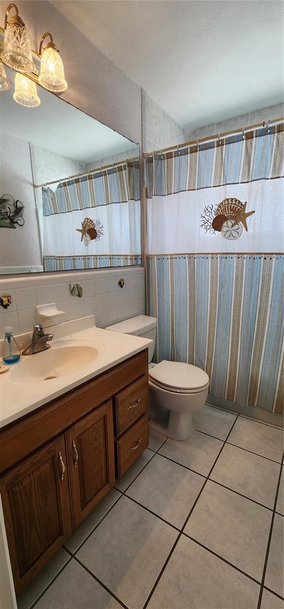 bathroom with tile patterned flooring, vanity, tile walls, and toilet