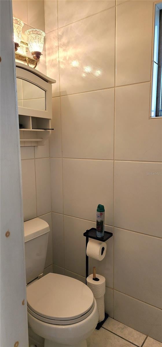 bathroom featuring tile patterned flooring, toilet, and tile walls