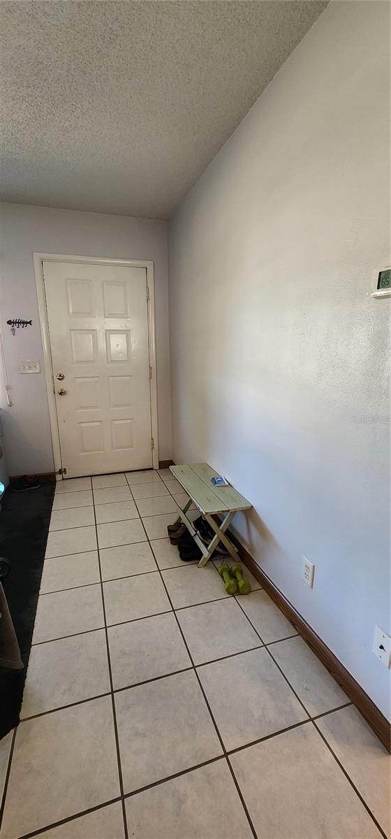 entryway featuring light tile patterned flooring and a textured ceiling