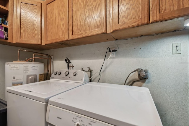 laundry area with water heater, washer and dryer, and cabinets