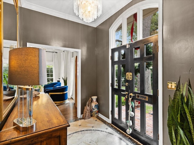 foyer entrance with french doors, an inviting chandelier, and ornamental molding