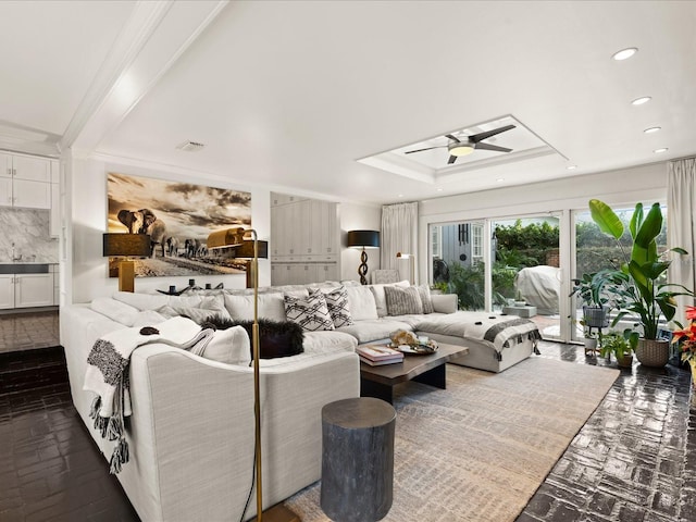 living room featuring a raised ceiling, ceiling fan, crown molding, and sink