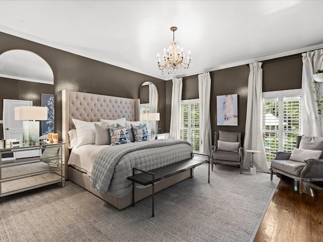 bedroom featuring hardwood / wood-style flooring, an inviting chandelier, ornamental molding, and multiple windows