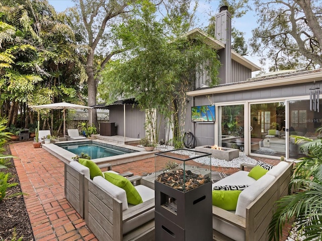 view of pool with an outdoor living space with a fire pit and a patio area