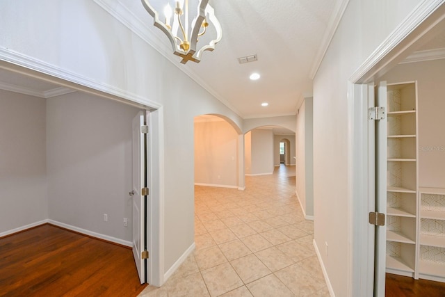 hall featuring ornamental molding, a notable chandelier, and light tile patterned flooring