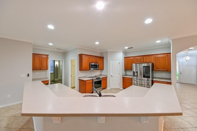 kitchen featuring a large island with sink, sink, appliances with stainless steel finishes, and a kitchen bar